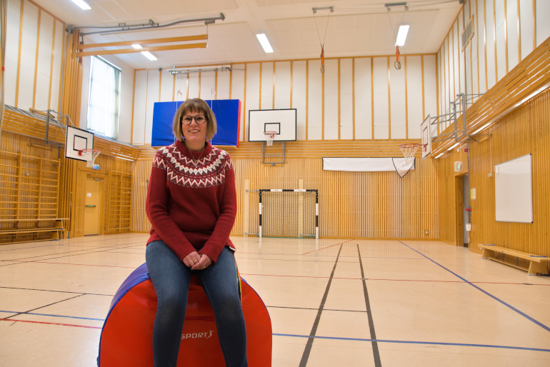En person sitter på ett gymnastikredskap i en gymnastiksal