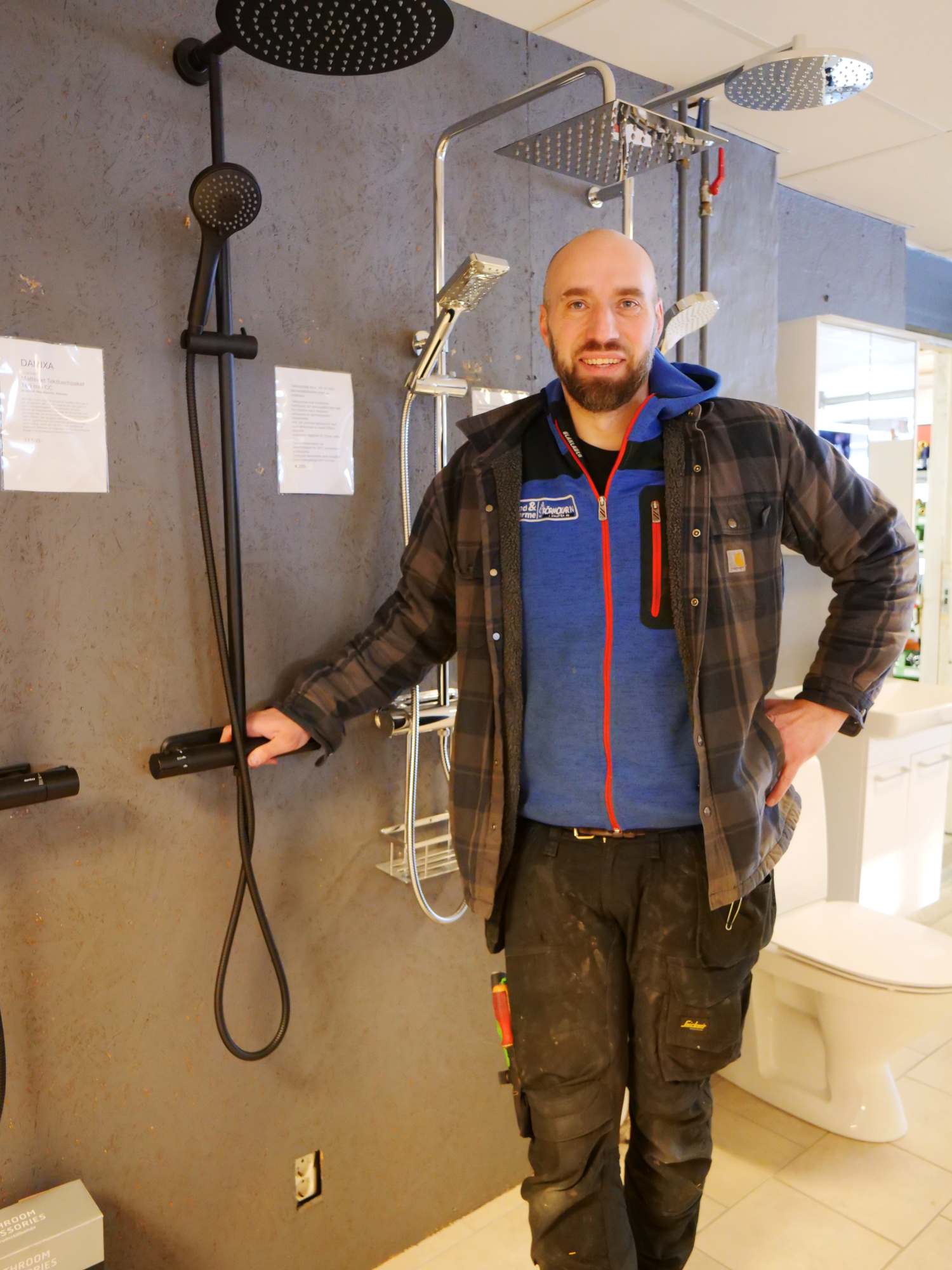 En person står framför flera duscharmaturer i en vvs-affär