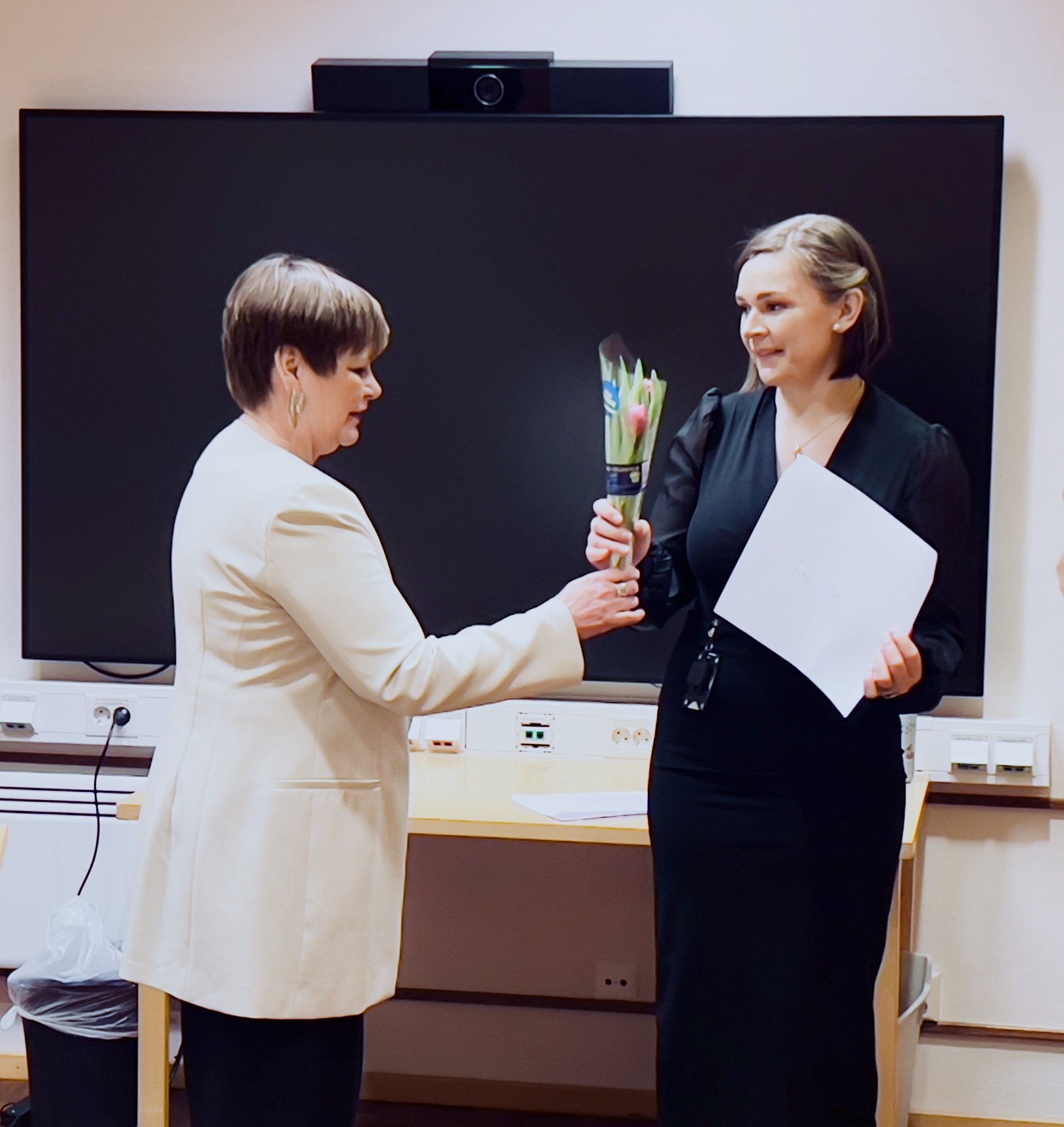 En student får blommor och ett stipendium av en politiker