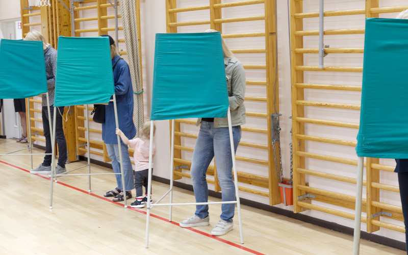 Väljare står bakom valskärmar och röstar