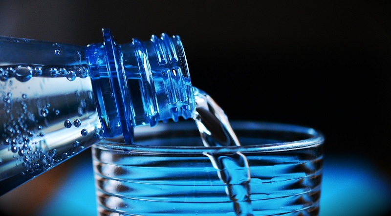 En flaska vatten som hälls upp i ett glas