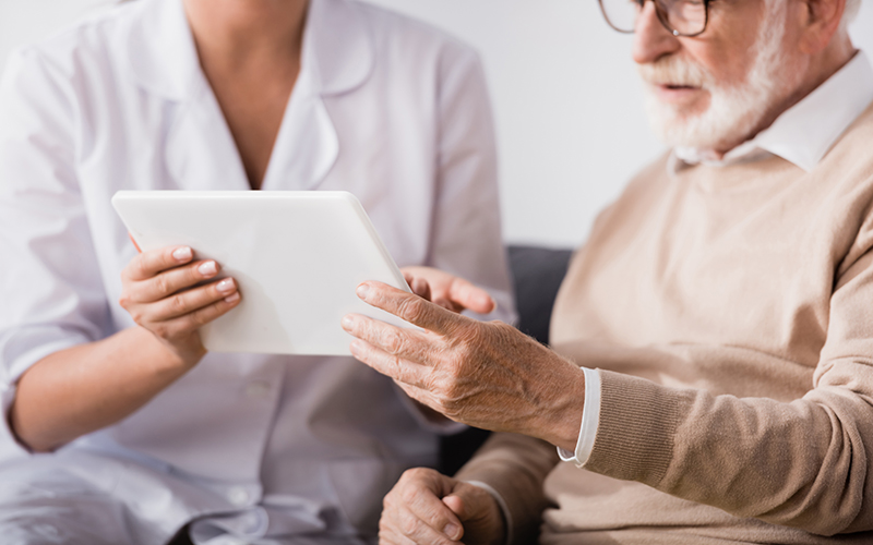 Hemtjänst personal hjälp äldre med tablet