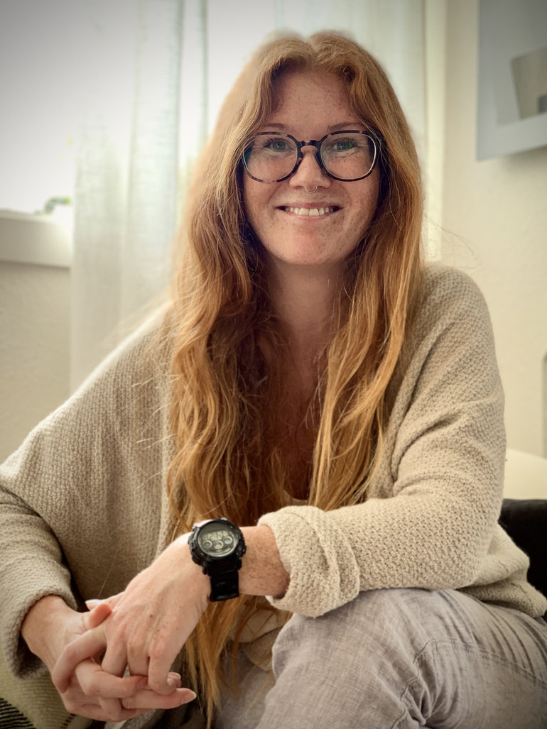 Porträtt av kvinna med rött hår och glasögon