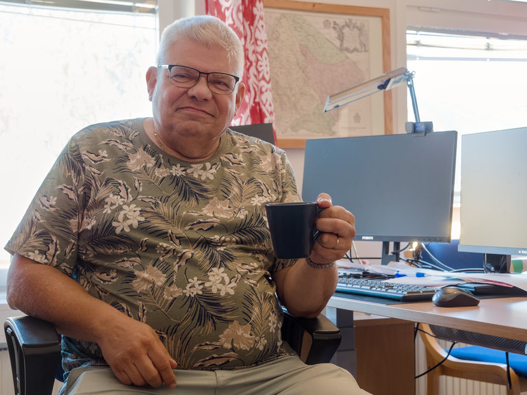 En man sitter på ett kontor med en kaffekopp