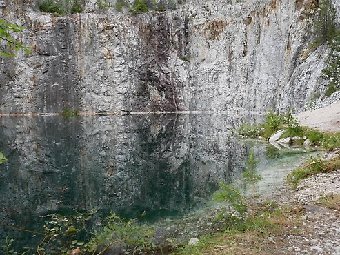 Bild på den gamla Edselegruvan, med dess bergvägg och klara vatten